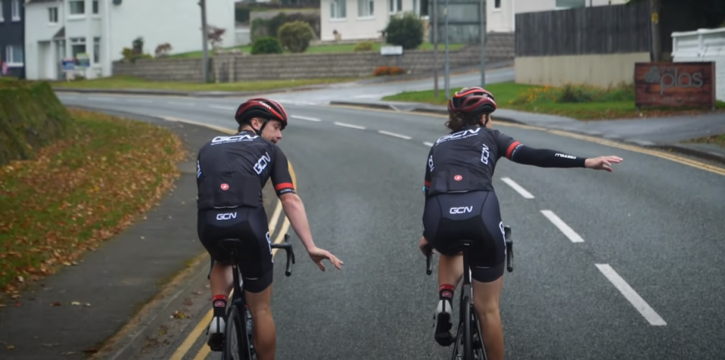 Two cyclists on the road indicating a right turn