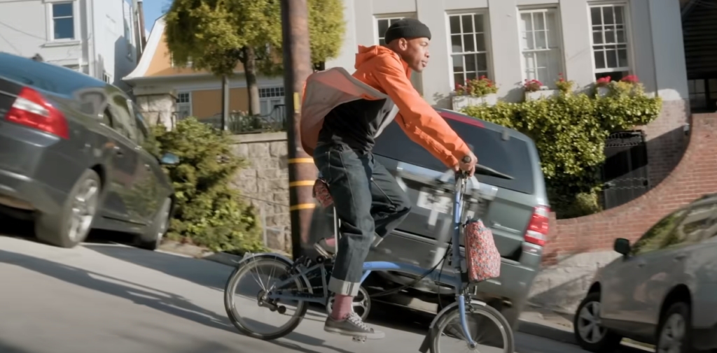 Man riding a bicycle on a downward sloping road